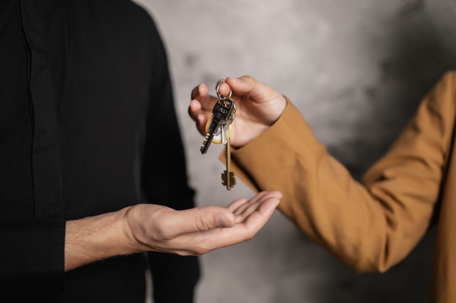 person handing someone else house keys