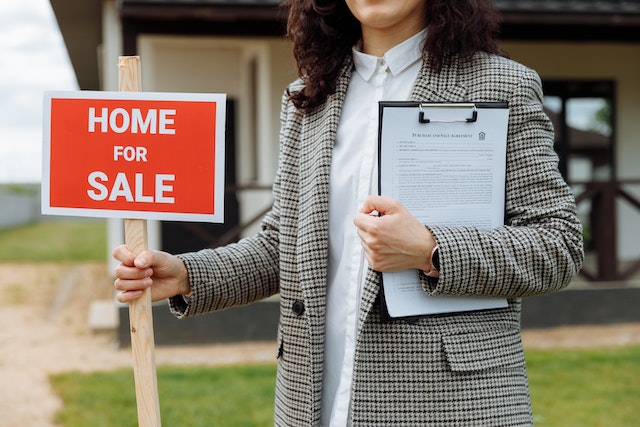 real estate agent holding home for sale sign