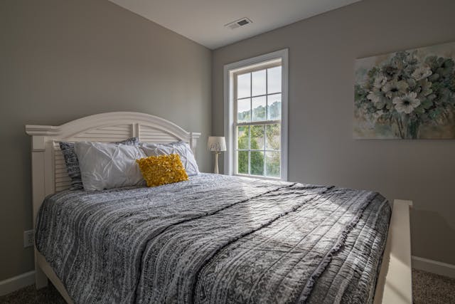 a bedroom with blue bedding and yellow throw pillows and a large window