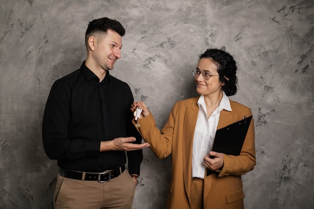 person in a tan jacket handing someone house keys